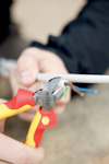 En person håller en avbitartång från Wiha och klipper av en kabel med flera kopparledare.