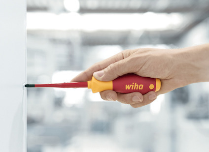 Hand som håller en skruvmejsel märkt "wiha" mot en vit yta.