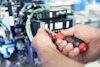 Person som använder en röd och svart skruvmejsel för att justera en elektronisk komponent.