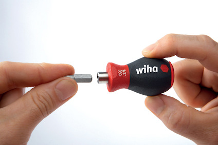 Två händer håller en bitsmejsel och en utbytbar bit. Mejselskaftet är märkt med "Wiha" och "3869".