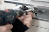 En person använder en borrmaskin med en socket fäste på en metalldel.