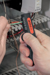 Hand som håller en tang med "Wiha" tryckt på handtaget, greppande färgade elektriska ledningar.