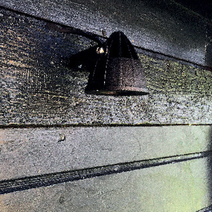 Liten svart lampa monterad på en vägg av gröna träpaneler.