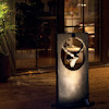 En dekorativ metallskulptur med en cirkulär form och en hjortdesign, placerad på en träveranda omgiven av växter.