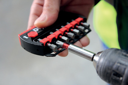 Närbild av en hand som håller en uppsättning bits, varav en sitter i en skruvdragare.