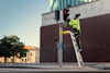 Person arbetar på en trafiksignal på en stege, iklädd neongul skyddsklädsel.
