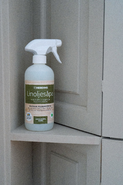 Flaska med Herdins Linoljesåpa på en hylla, beige bakgrund. Klassisk allrengöring, linoljebaserad.