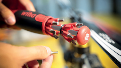 Närbild av ett multitool med flera bits. Texten "26 in One" syns på verktygets topp.