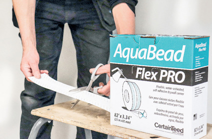 Person klipper AquaBead Flex PRO-produkt från en kartong på en träbänk.