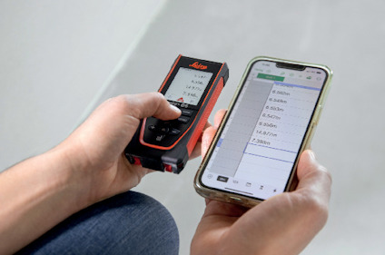 Person som håller en avståndsmätare och en smartphone med en app som visar mätresultat.