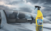 Gul sprayflaska Rain-X 2in1 Glass Cleaner på våt bilhuv, molnig himmel i bakgrunden.