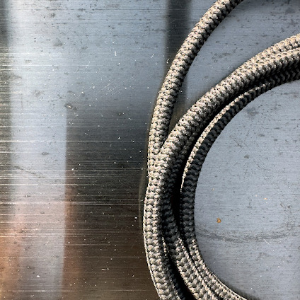 Flätad metallslang på en grå, polerad metallisk yta.