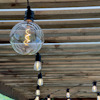 Glödlampa med synliga glödtrådar hänger under ett trätak. Flera lampor i rad.