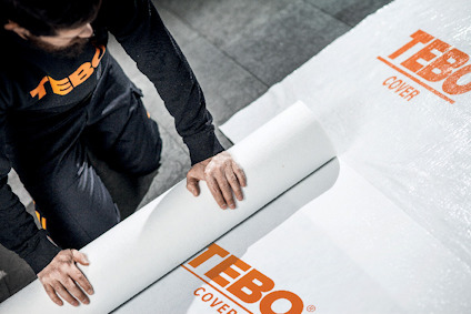 Person rullar ut vit materialduk med orange text "TEBO COVER".