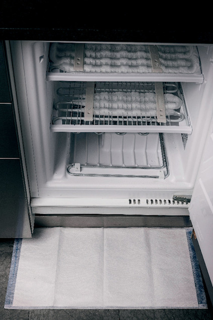 Öppen kyl eller frys med frostfri teknik, isbildning och fuktuppsamlingsmatta på golvet framför.