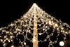 Julgransliknande ljusinstallation med vita ljusglober mot en mörk bakgrund.