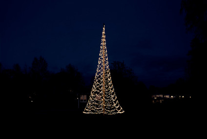 Mörk himmel med en konformad julbelysning av vita ljusslingor.