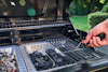 Hand håller termometer över en gasolgrill med kolbriketter och träflis i metallfack.