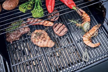 Grill med mat, inklusive biffar, räkor, paprika och broccolini, på varma galler.