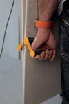 En person håller ett beige byggskivematerial med ett orange handtag.