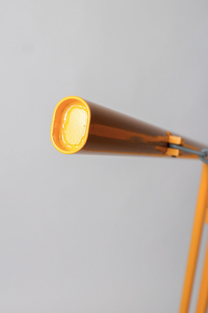 Orangelyktlampa i vintage design, med avlång skärm och rund glödlampa, mot en grå bakgrund.