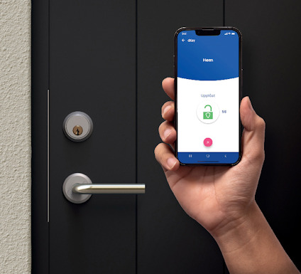 Hand håller en smartphone som visar "Uppslost" med bild av ett upplåst hänglås; en dörr med silverfärgat handtag syns i bakgrunden.