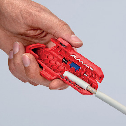 Hand håller ett rött verktyg för att skala en vit kabel.
