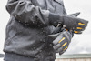 Person i vinterjacka och handskar står utomhus i snöfall.
